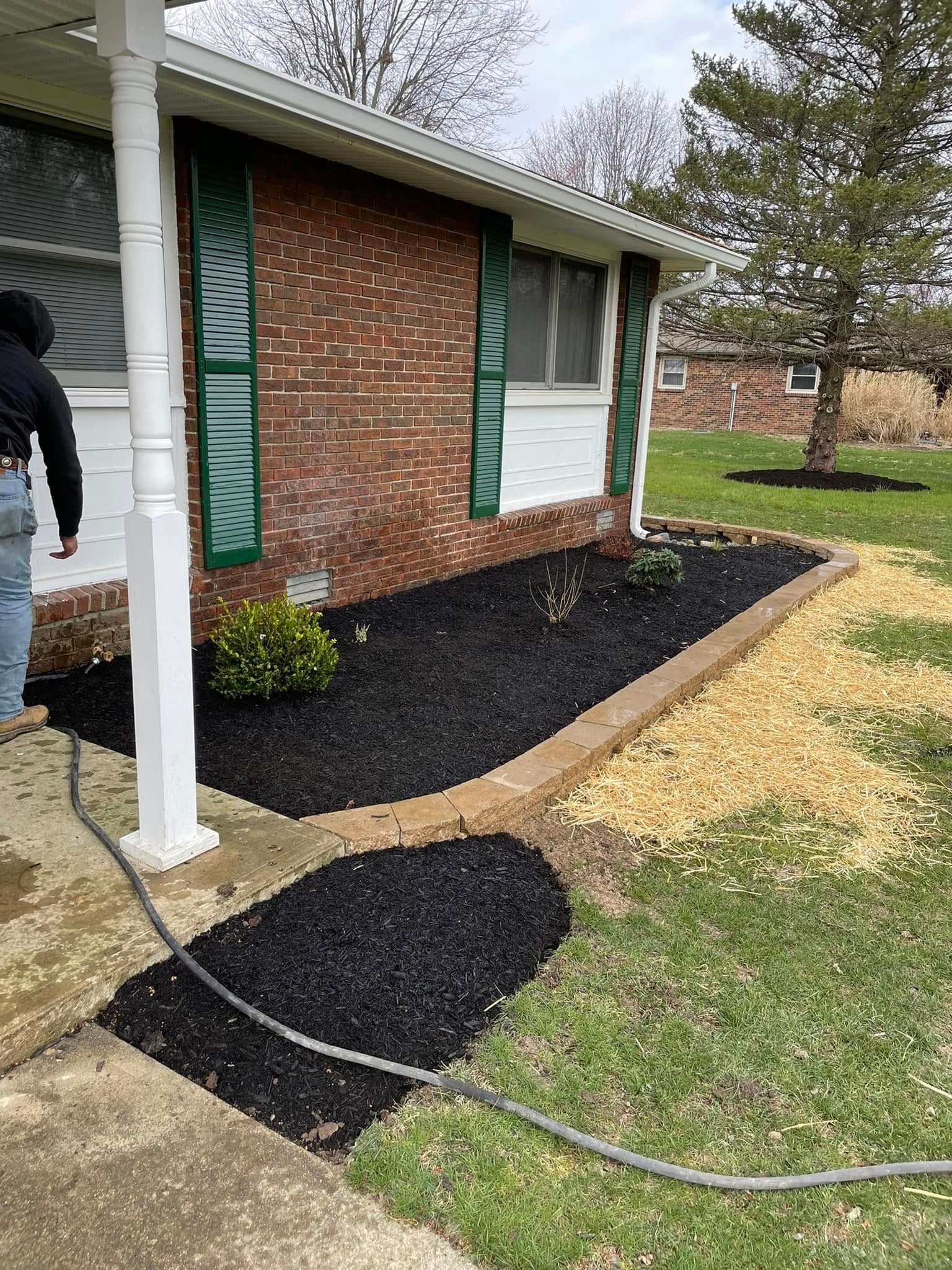 A man is standing in front of a house with a hose attached to it.