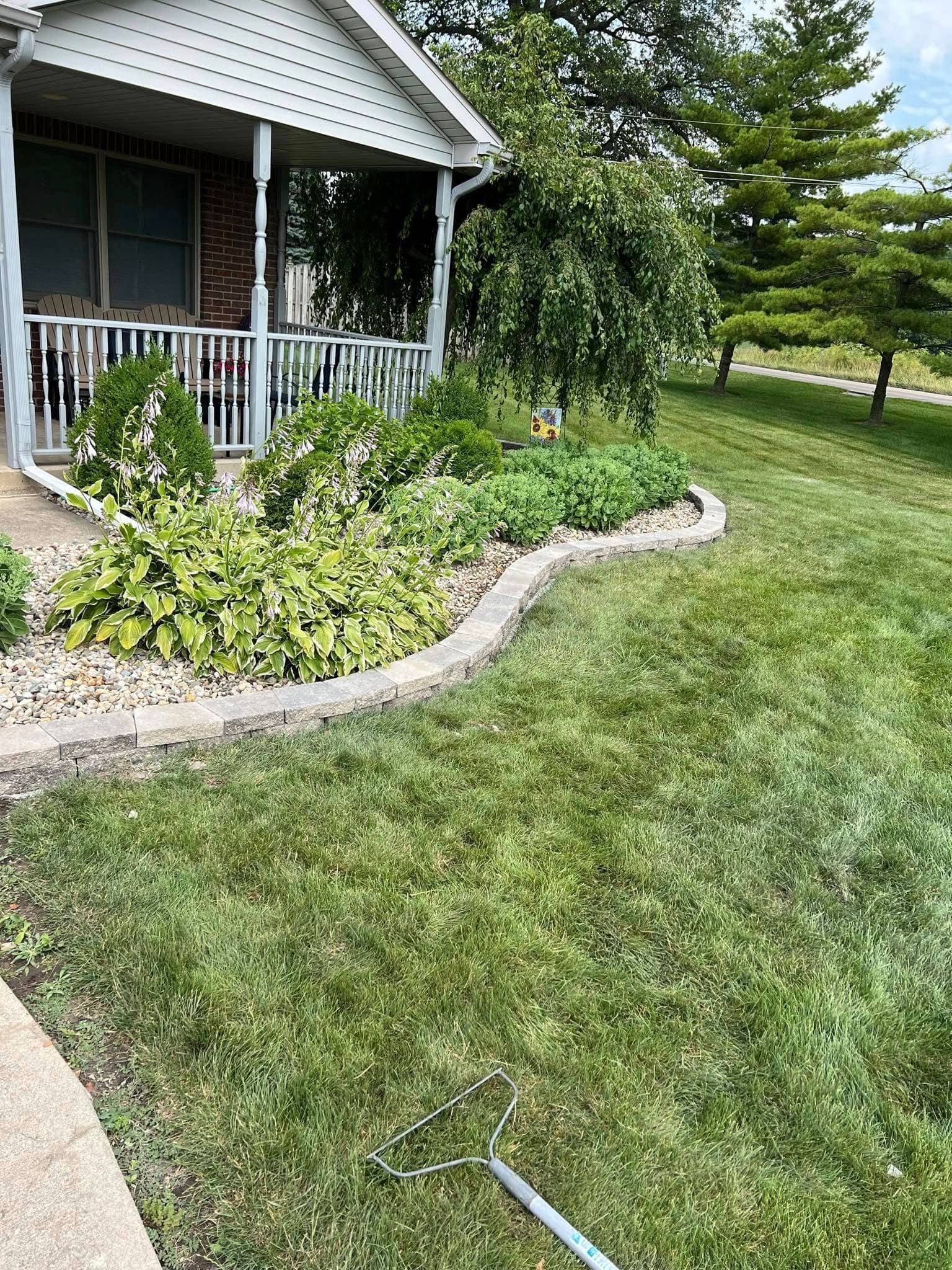 A rake is sitting in the grass in front of a house.