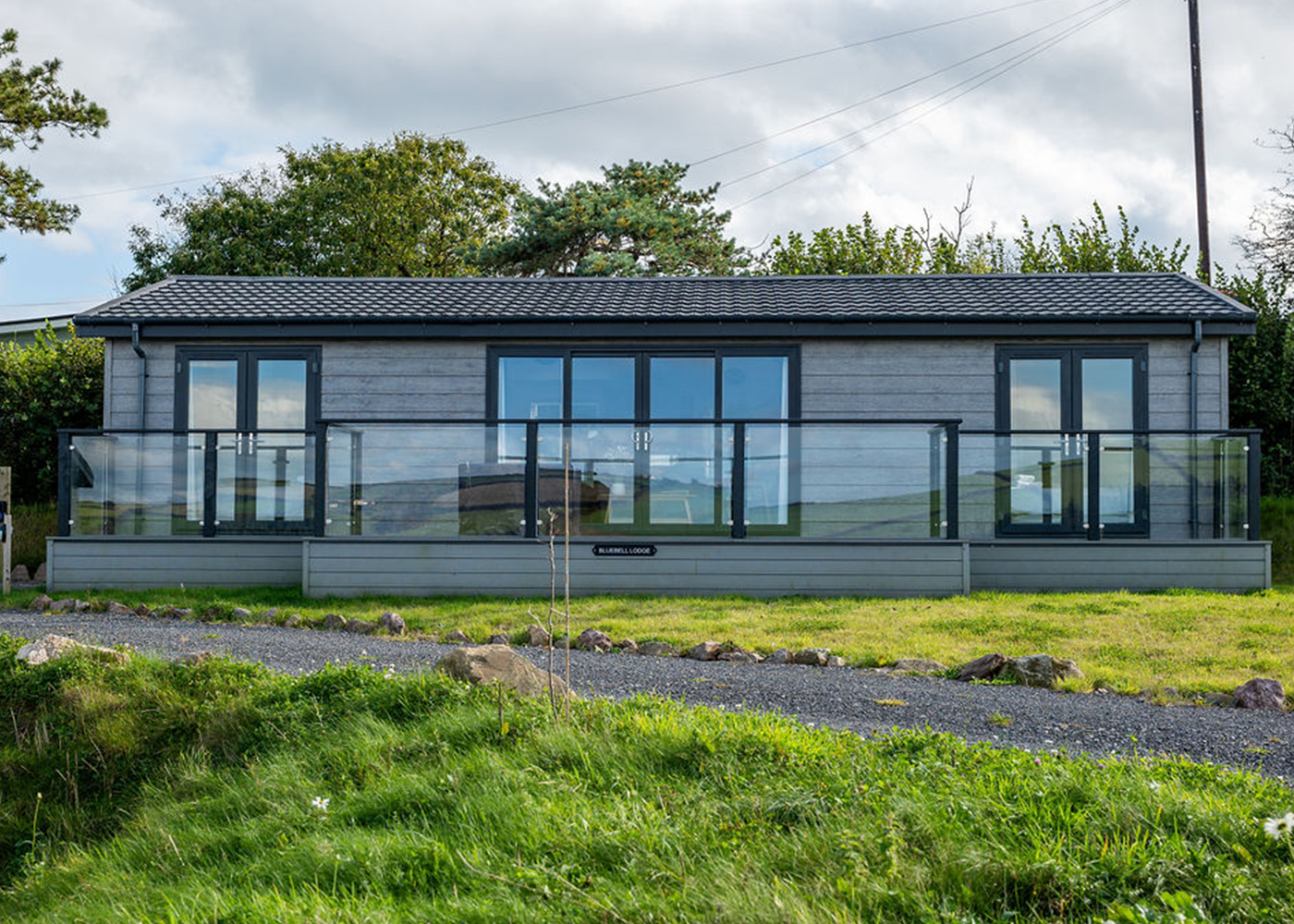 A large house with a lot of windows is sitting in the middle of a grassy field.