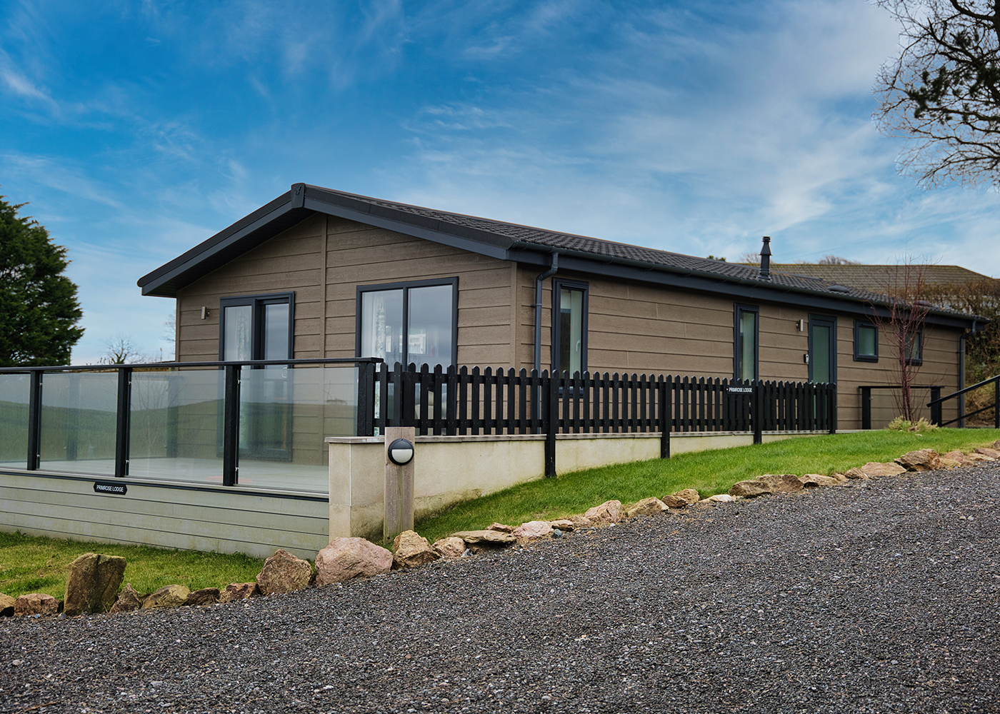 A large house with a fence around it is sitting on top of a hill.