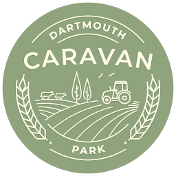 A logo for dartmouth caravan park with a tractor in the middle of a field.