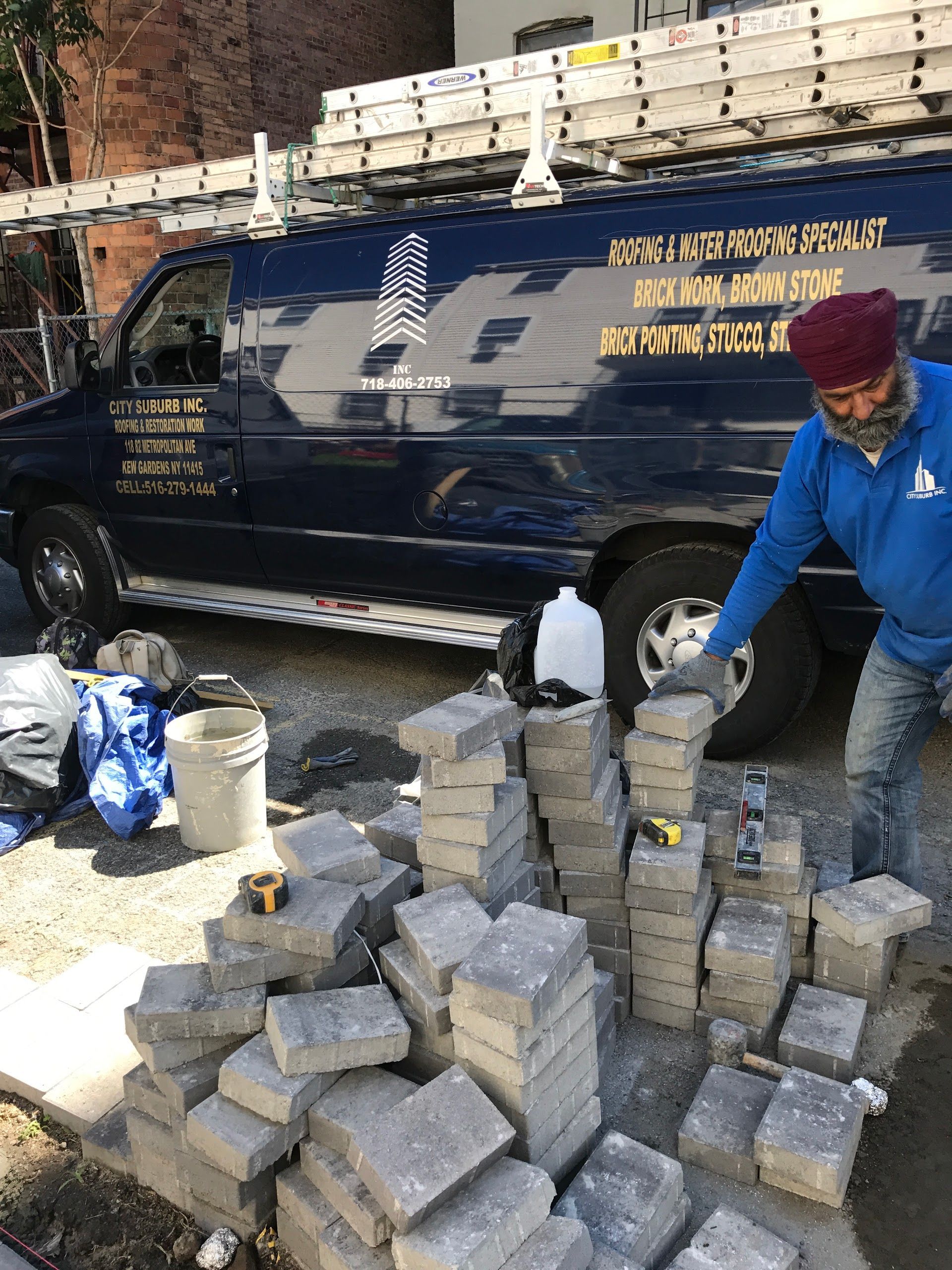 A man is standing next to a pile of bricks in front of a van.