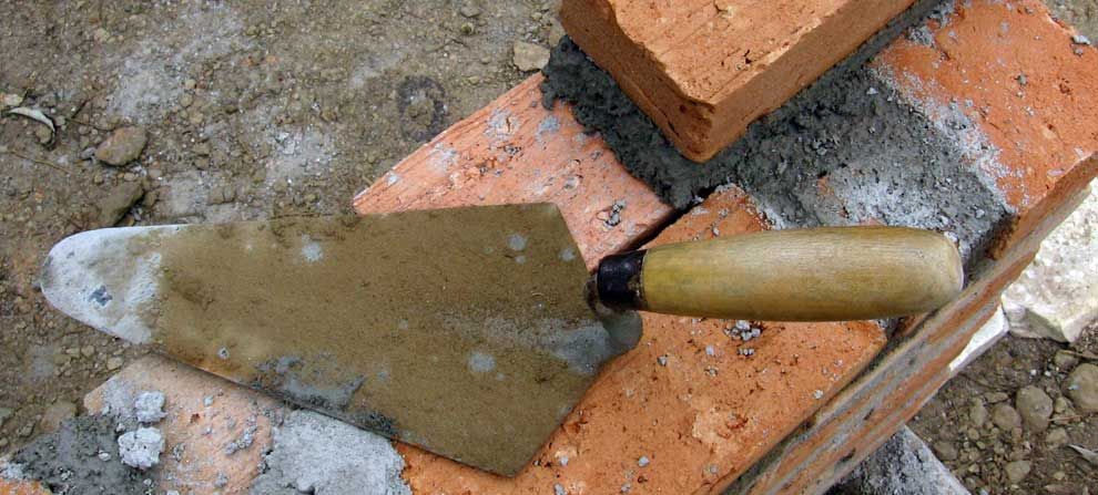 A trowel is sitting on top of a pile of bricks.