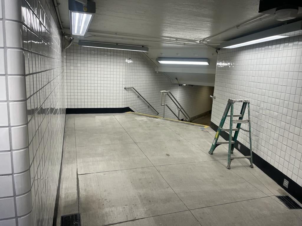 A ladder is sitting in the middle of a subway tunnel.