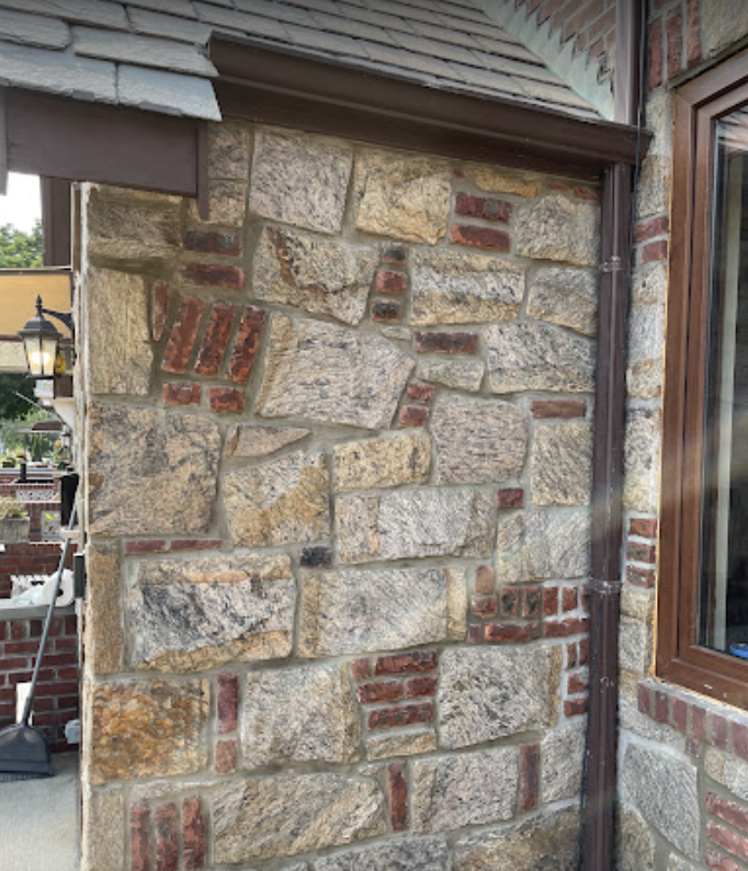 A stone wall with a window and a gutter on it