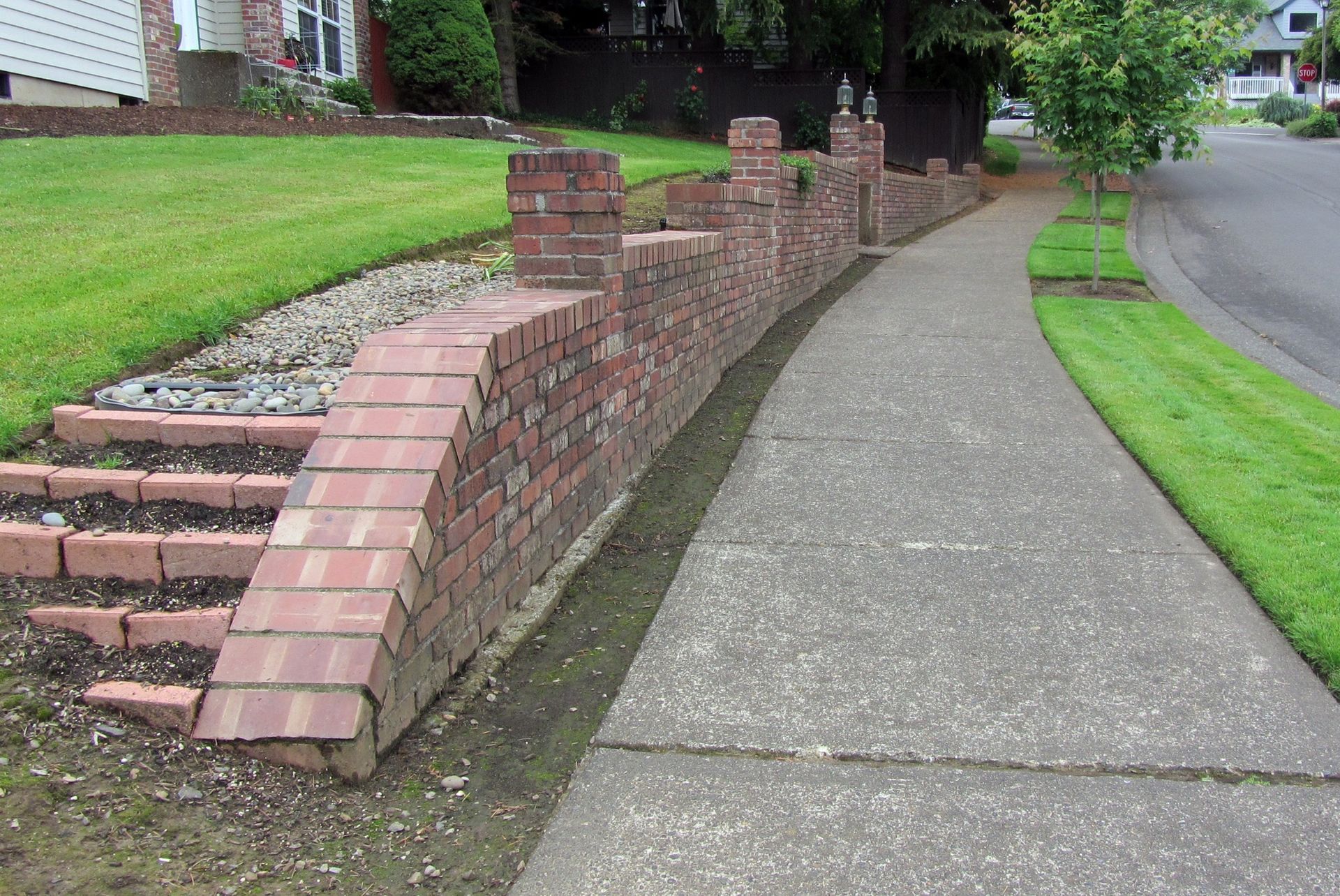 A sidewalk with a brick wall along the side of it