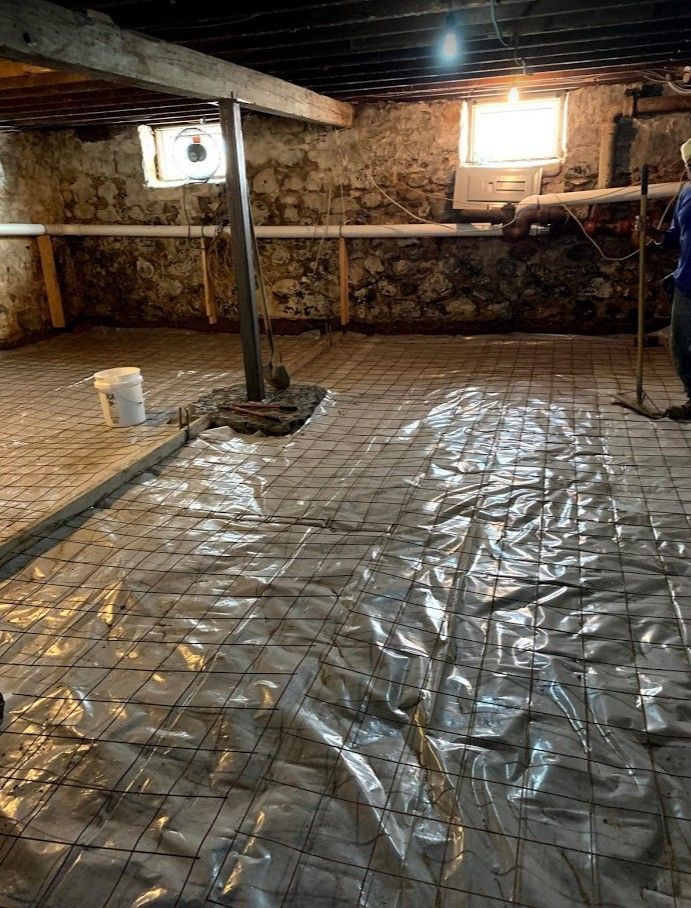 A man is standing in a basement covered in plastic.