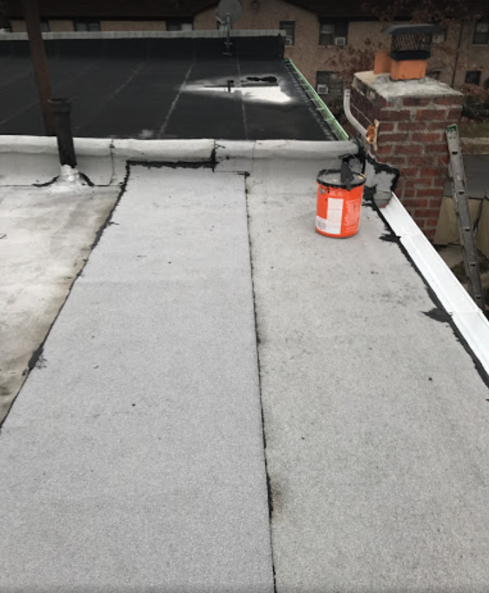 A bucket of paint sits on the roof of a building