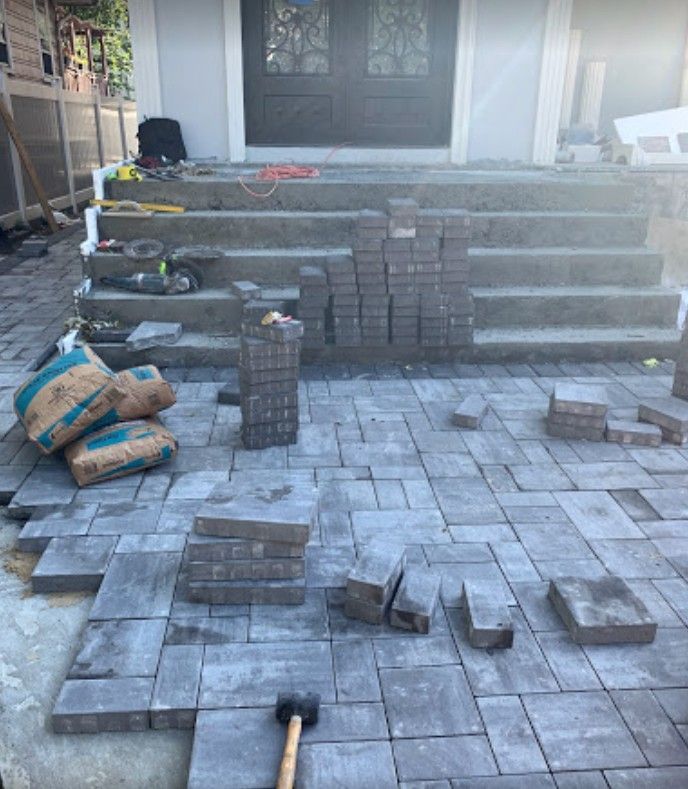 A brick walkway is being built in front of a house.