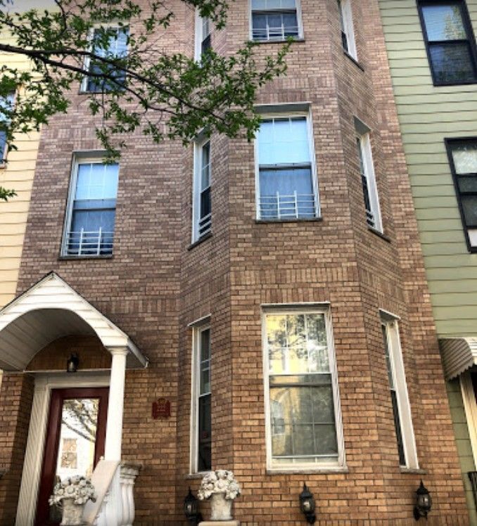 A brick building with many windows and a porch