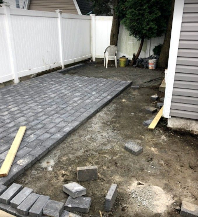 A patio is being built in the backyard of a house.
