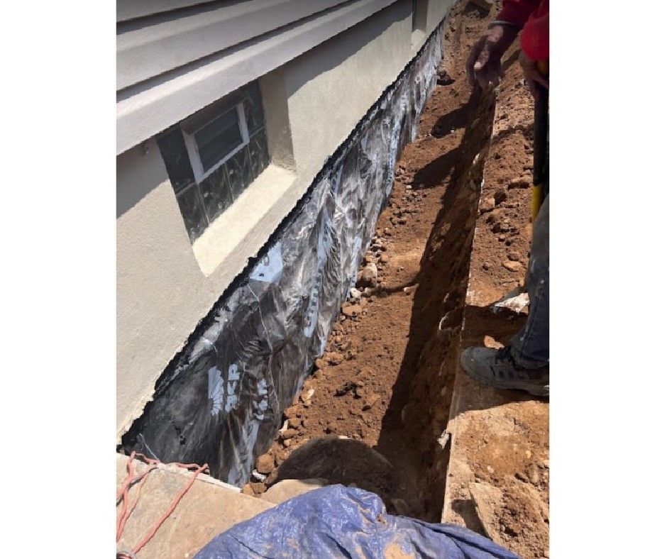 A person is digging a hole in the ground in front of a house.