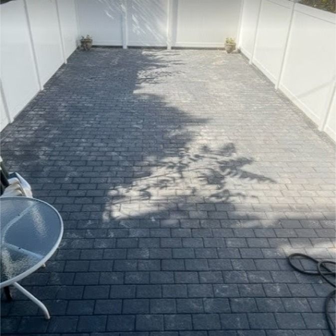 A patio with a table and chairs and a white fence.