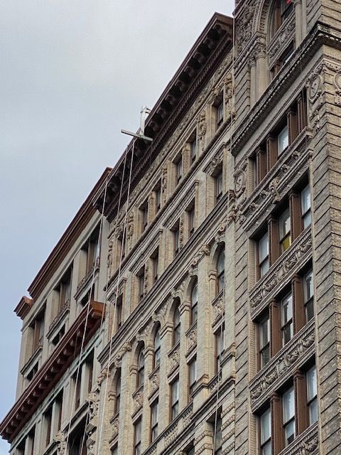 Ornate beige apartment building facade viewed from below against a cloudy sky