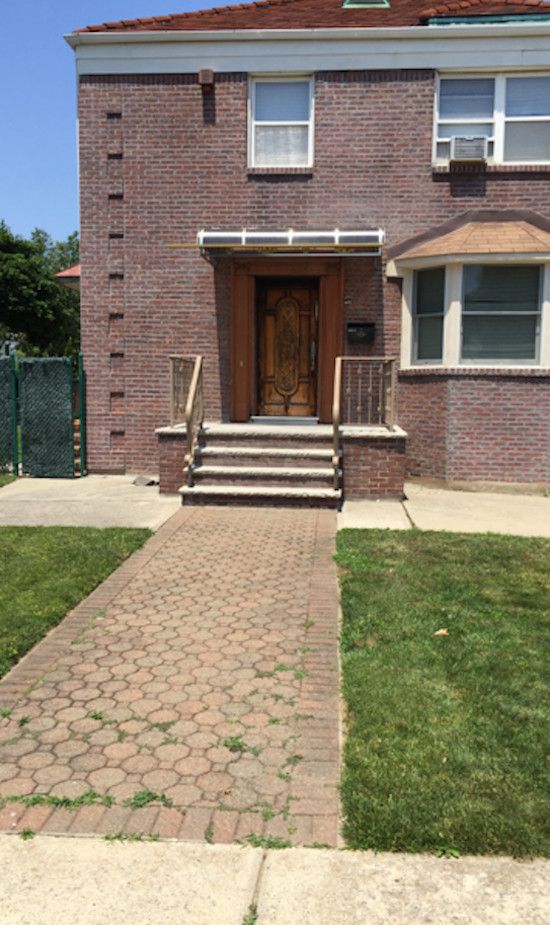 A brick house with a brick walkway leading to the front door.