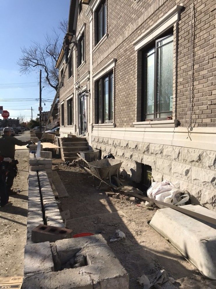 A man is standing in front of a brick building under construction.