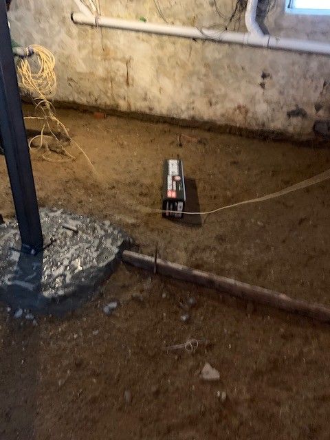 A machine is sitting on the ground in a basement next to a window.