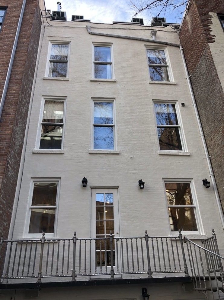 A white brick building with a balcony and stairs