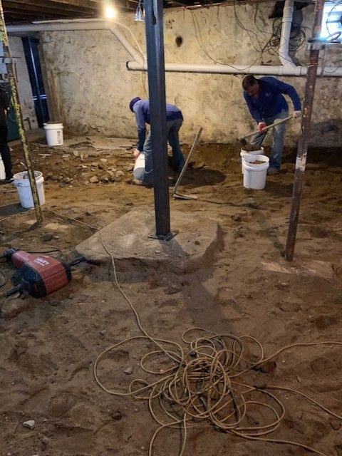 Two men are working in a basement with buckets and shovels.