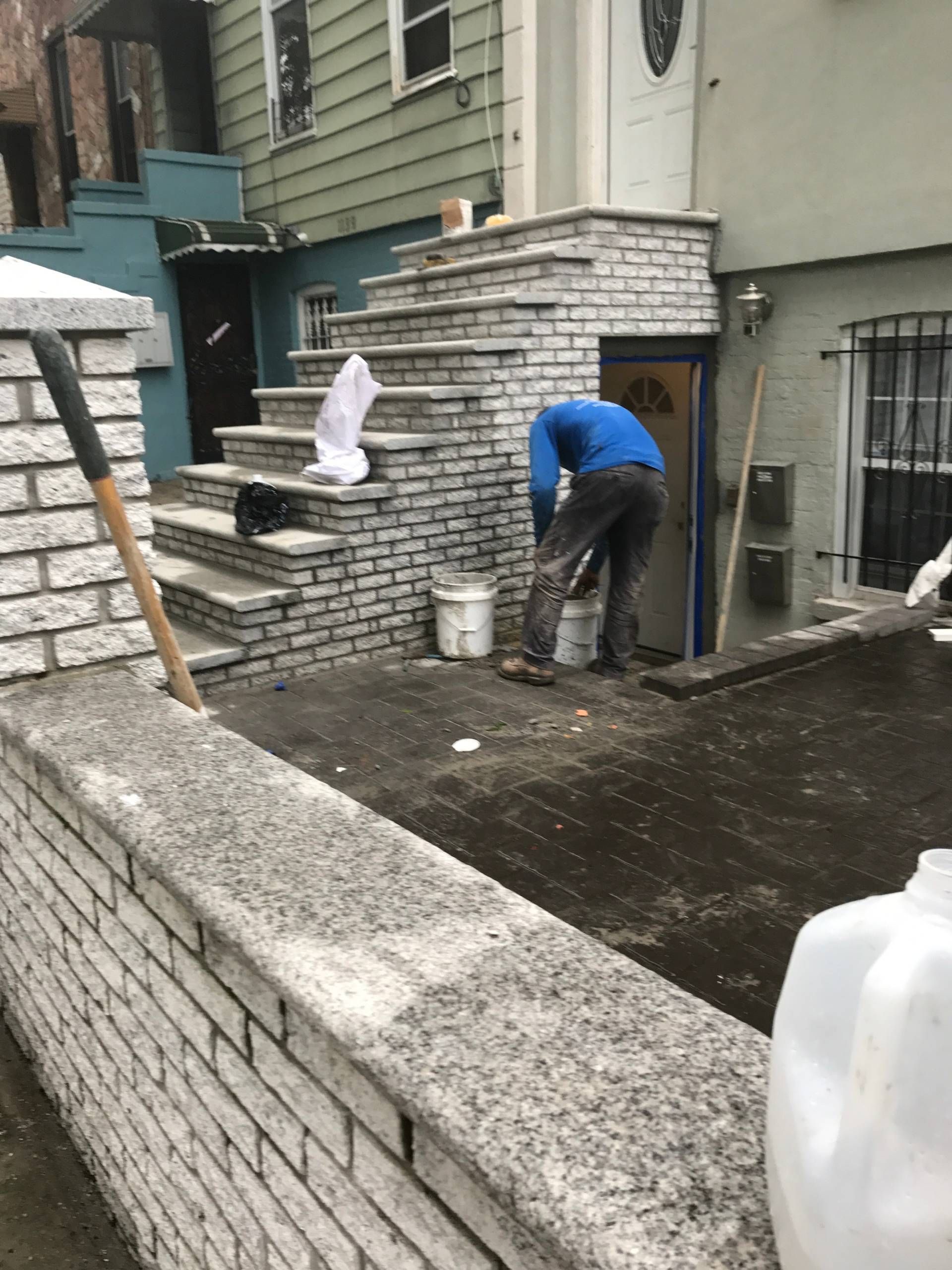 A man is working on a brick wall in front of a house