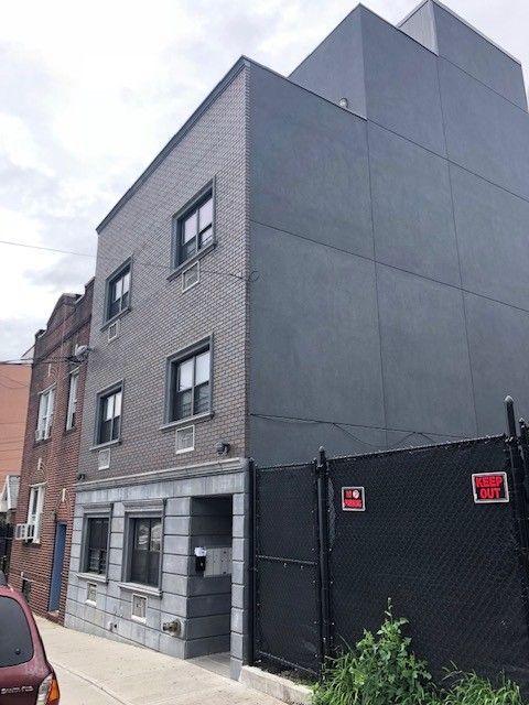 A brick building with a red car parked in front of it