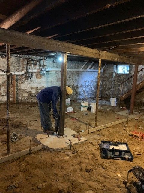 A man is working in a basement under a staircase.