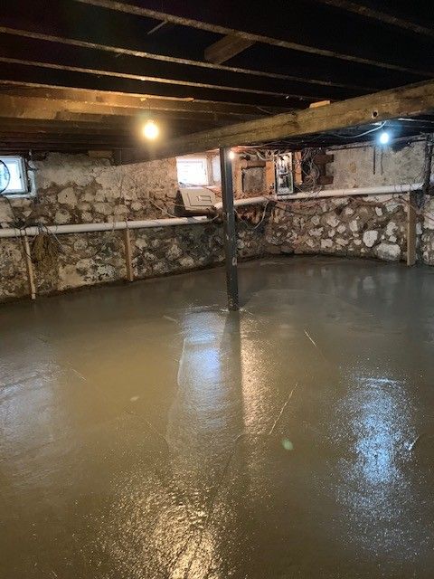 A basement with a concrete floor and a stone wall.
