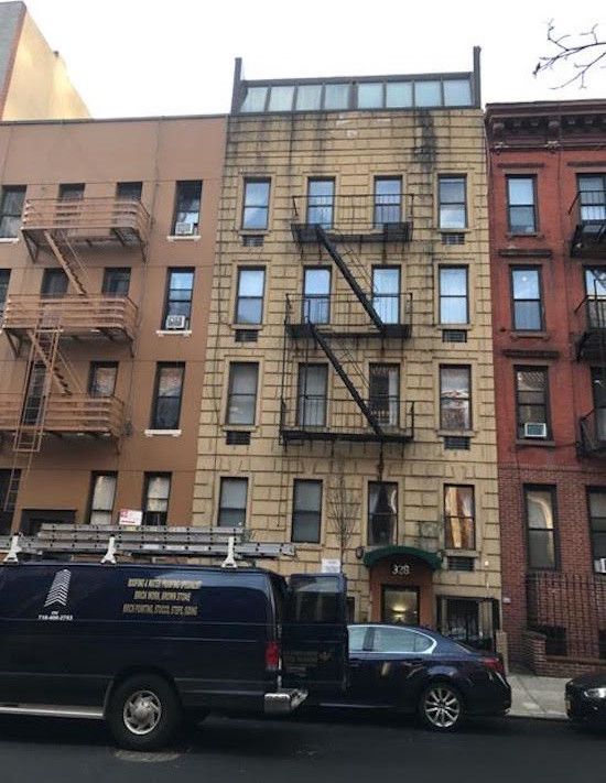 A building with a fire escape and a van parked in front of it