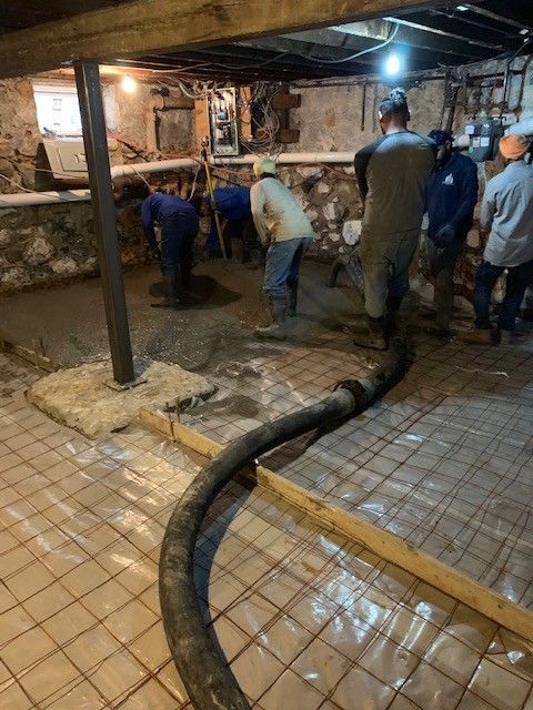 A group of men are working on a concrete floor in a basement.