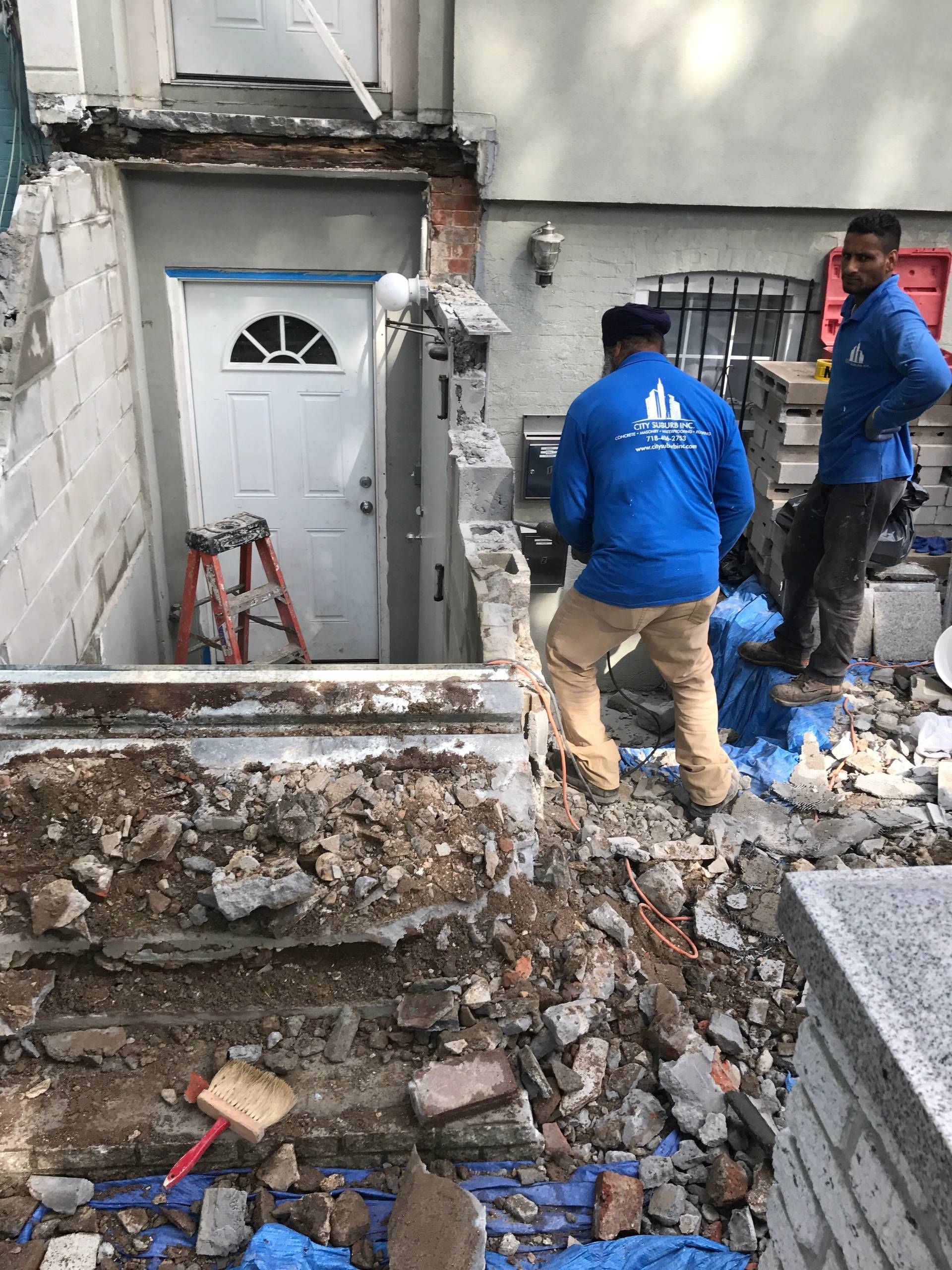 A couple of men are standing in a pile of dirt in front of a building.