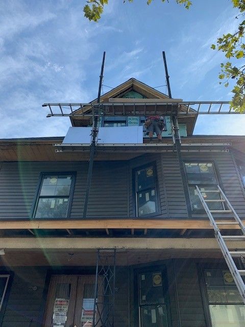 A man is working on the roof of a house with a ladder.