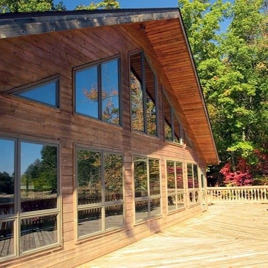 A large wooden house with lots of windows and trees in the background