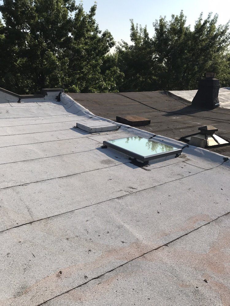 A roof with a skylight on it and trees in the background