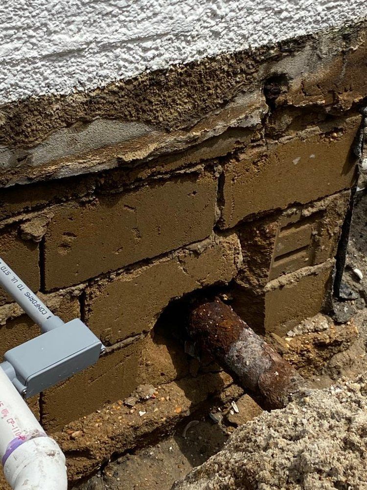 A pipe is coming out of a hole in a brick wall.
