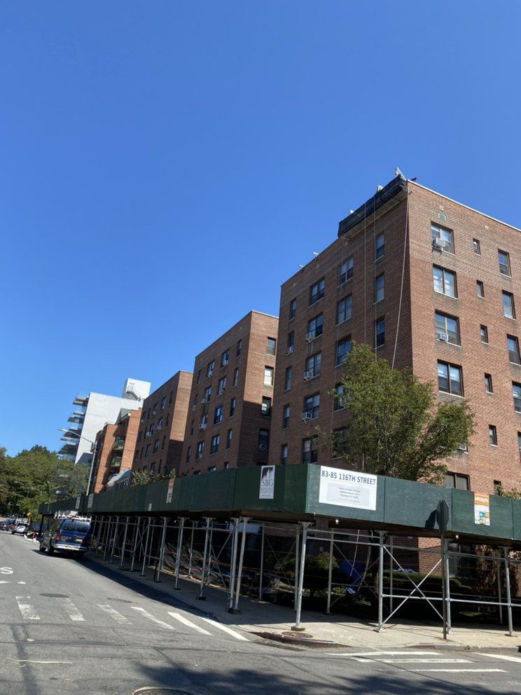 A large brick building is under construction on the side of the road.