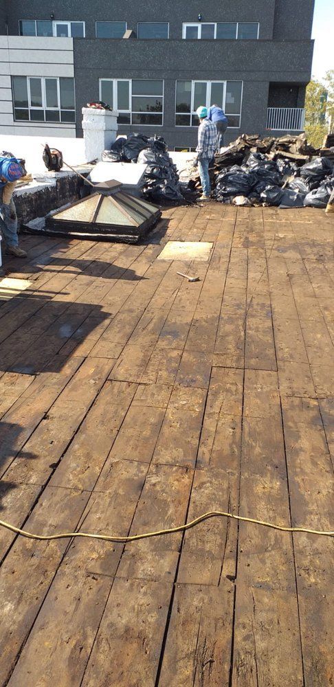 A man is standing on a wooden deck next to a building.