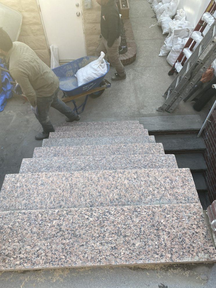 A man pushing a wheelbarrow down a set of stairs