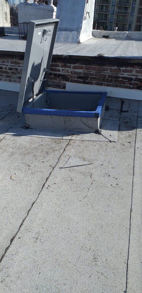 A roof with a stainless steel hatch open on it.