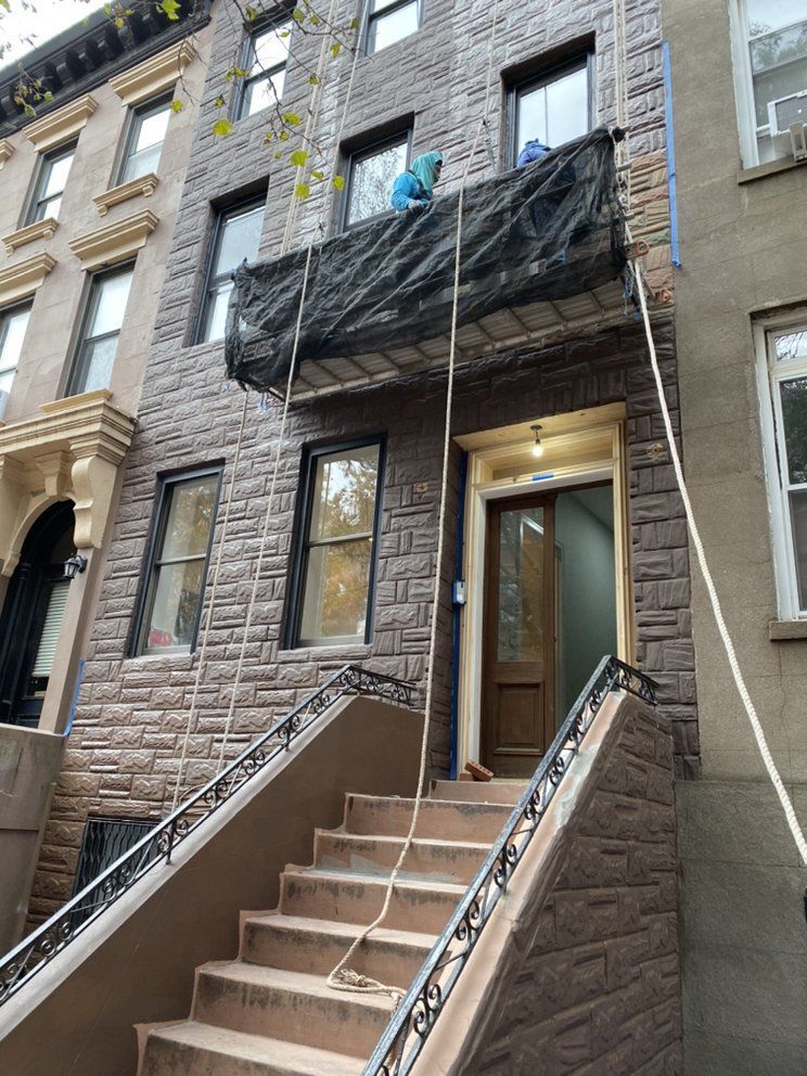 A man is standing on a balcony of a brick building.