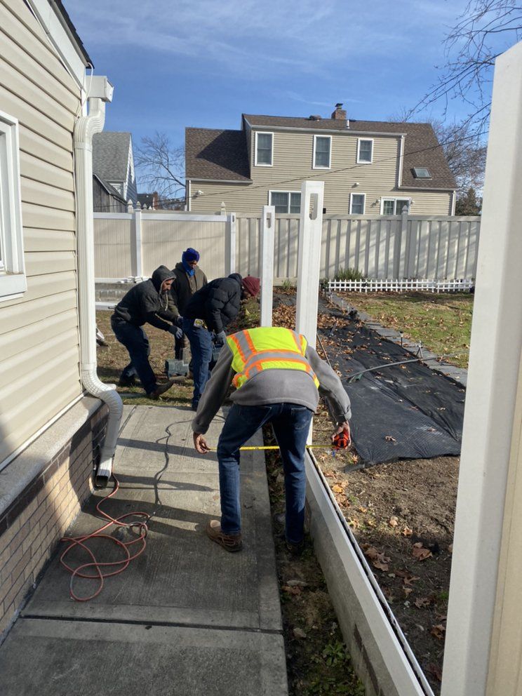 A group of men are working on a fence in front of a house.