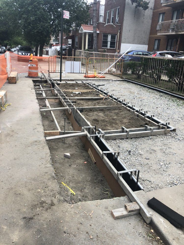 A concrete walkway is being built on the side of the road