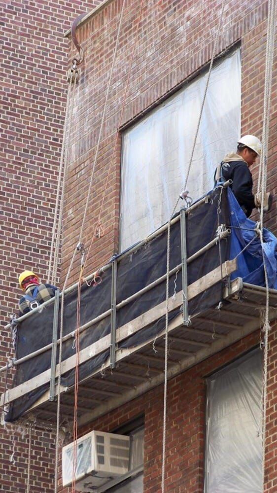 A man is standing on a scaffolding on the side of a building.