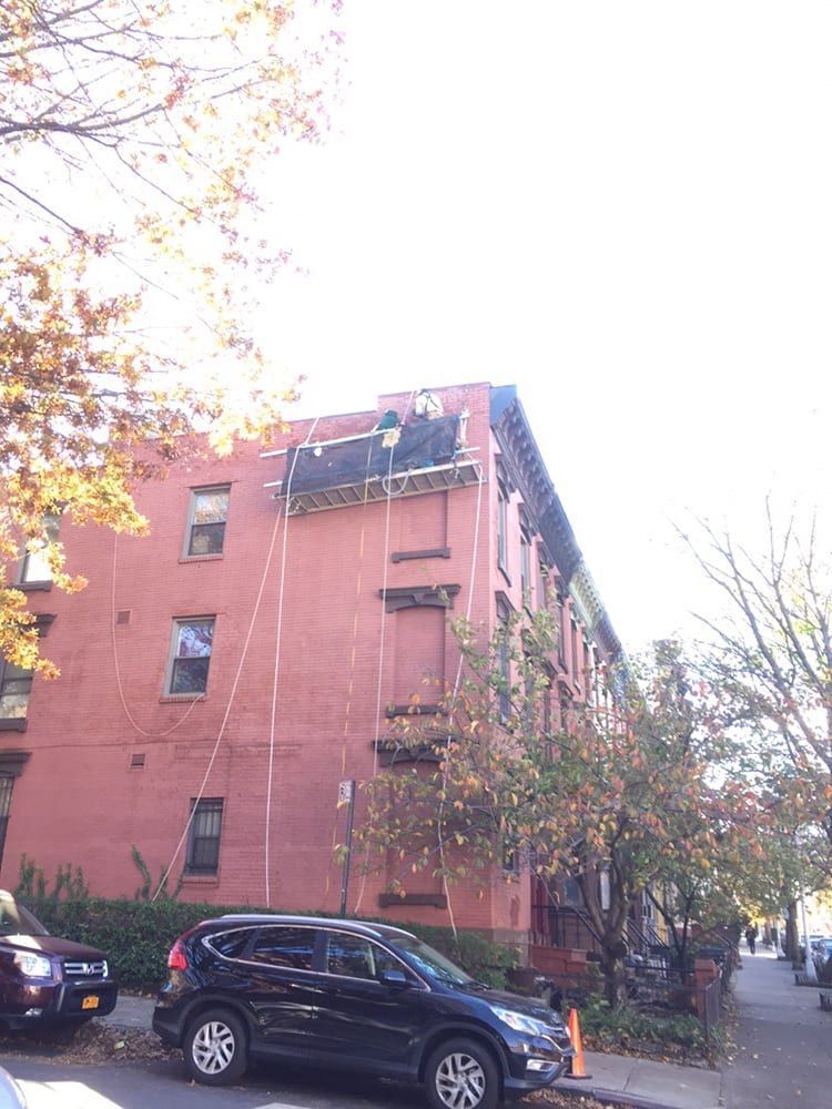 A car is parked in front of a large brick building.