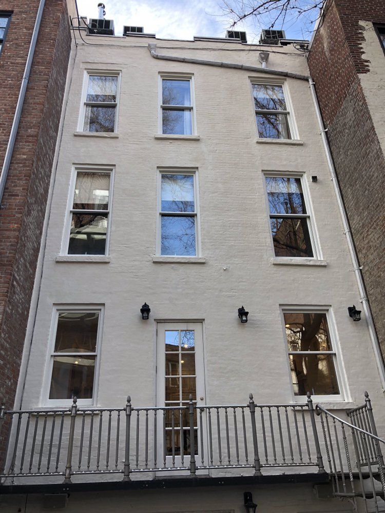 A white brick building with a balcony and stairs