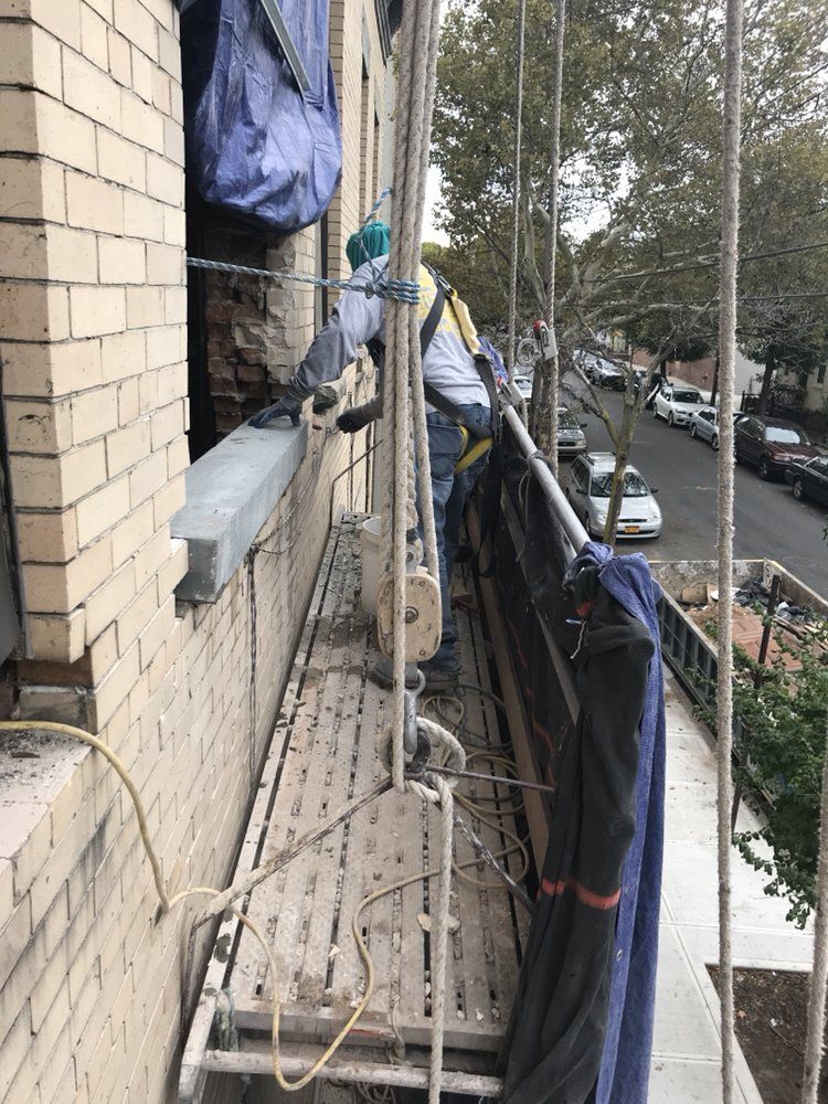 A man is standing on a scaffolding on the side of a building.