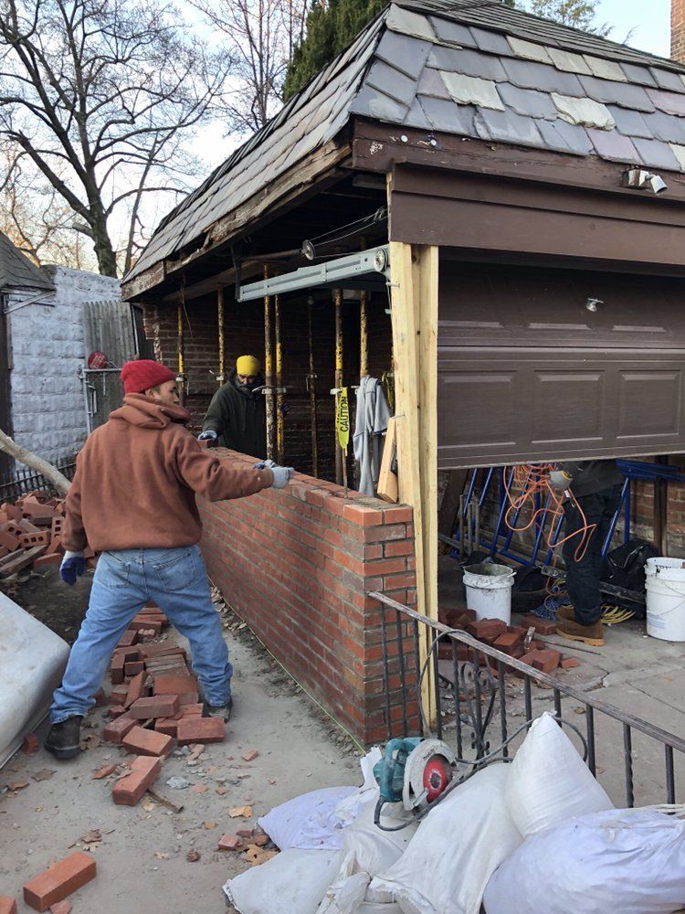 A man is laying bricks on the side of a building.