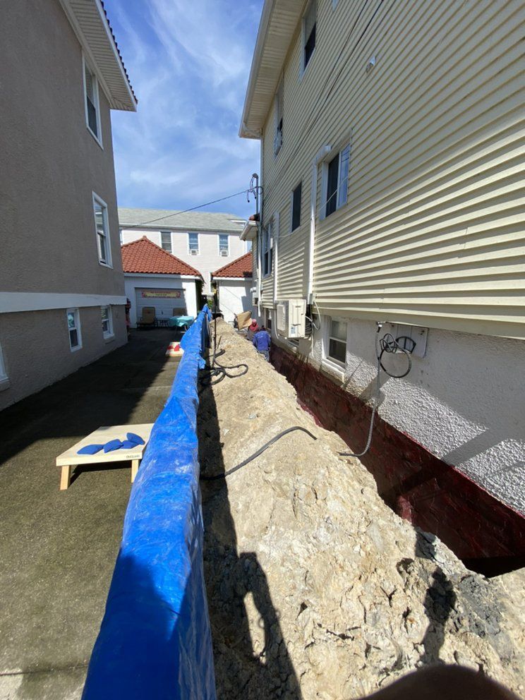 A narrow alleyway between two houses with a blue tarp on the side of the road.