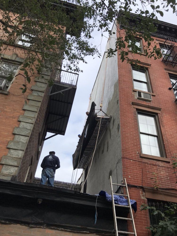 A man standing on the roof of a building with a ladder