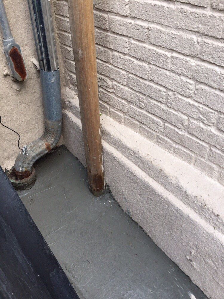 A wooden pole is sitting next to a brick wall.
