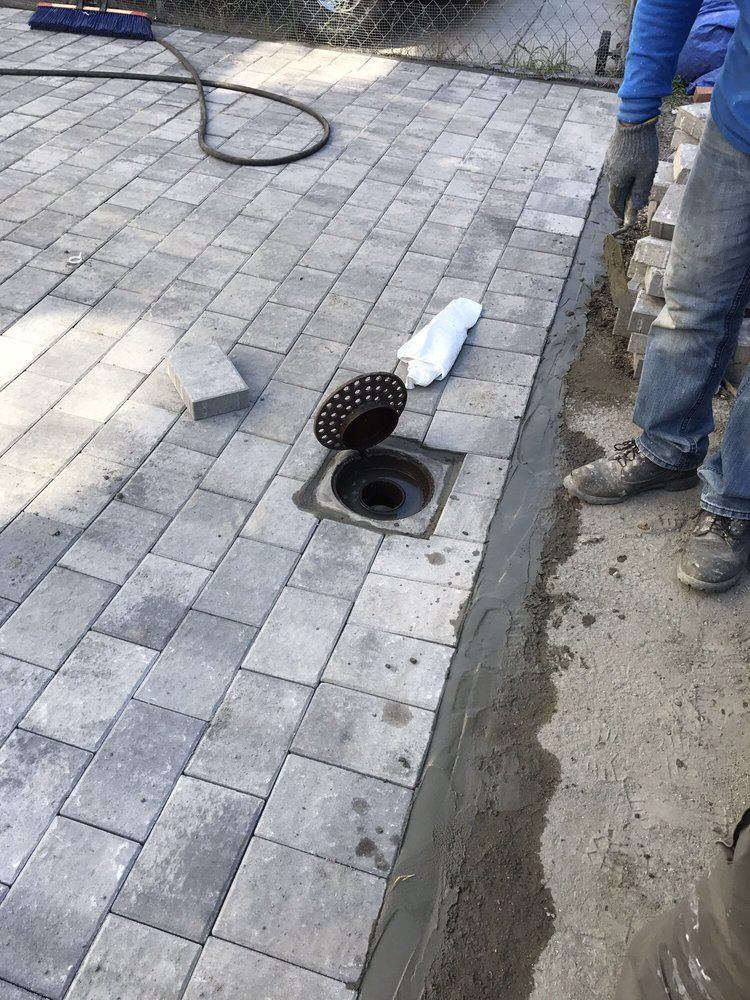 A manhole cover is open on a brick walkway.